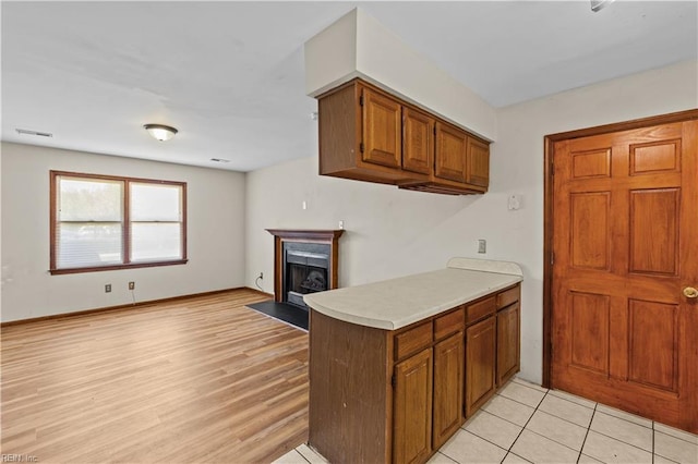 128 Glen Echo Dr, Norfolk, VA 23505 - kitchen with brown cabinets, light countertops, a fireplace with flush hearth, and light wood-style flooring