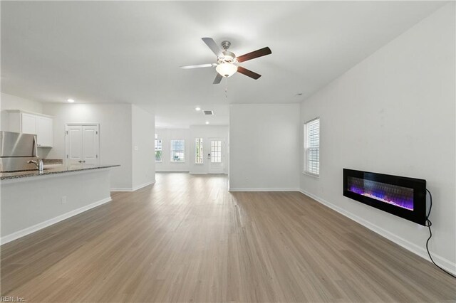 1506 Waltham Ln, Newport News, VA 23608 - unfurnished living room with a ceiling fan, a glass covered fireplace, light wood-style flooring, and recessed lighting