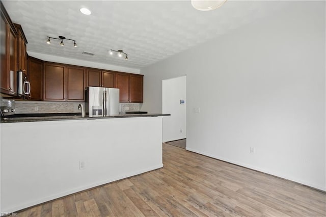 3494 Prices Fork Blvd, Suffolk, VA 23435 - kitchen with stainless steel appliances, dark countertops, a peninsula, decorative backsplash, and light wood-type flooring