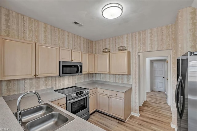 1010 Legends Way, Suffolk, VA 23435 - kitchen with stainless steel appliances, wallpapered walls, light brown cabinets, light countertops, and light wood-style flooring