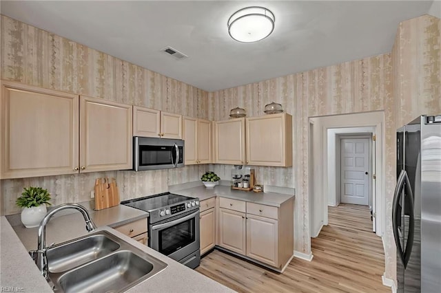 1010 Legends Way, Suffolk, VA 23435 - kitchen with stainless steel appliances, wallpapered walls, light wood-style floors, light countertops, and light brown cabinetry
