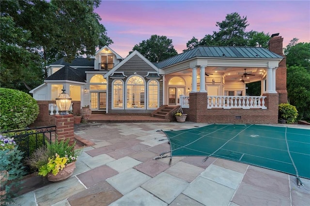 1845 N Alanton Dr, Virginia Beach, VA 23454 - back of property at dusk featuring a ceiling fan, brick siding, a chimney, a covered pool, and a standing seam roof