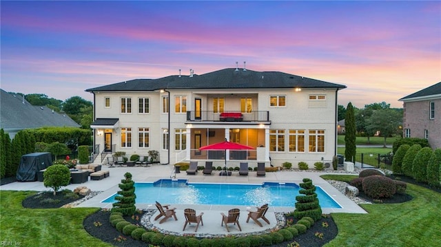 2716 Nestlebrook Trl, Virginia Beach, VA 23456 - back of house at dusk featuring a balcony, an outdoor living space with a fire pit, a patio, and an outdoor pool