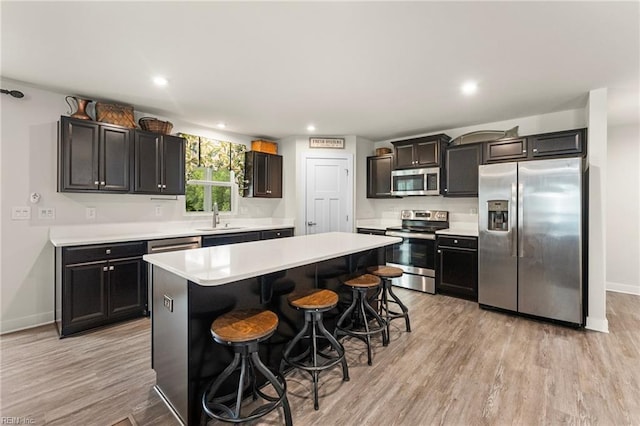 6957 Healy Ave, Gloucester, VA 23061 - kitchen featuring stainless steel appliances, a kitchen island, a kitchen breakfast bar, light countertops, and light wood-style floors