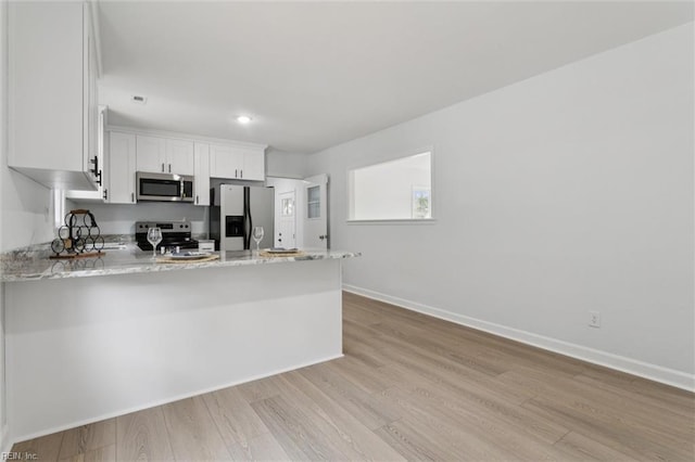 13067 Poor House Rd, Windsor, VA 23487 - kitchen with stainless steel appliances, a peninsula, white cabinets, light wood finished floors, and light stone counters