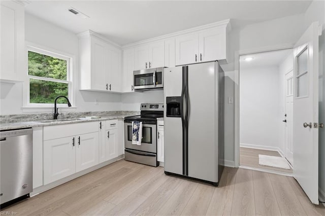13067 Poor House Rd, Windsor, VA 23487 - kitchen with appliances with stainless steel finishes, light wood-style floors, white cabinetry, and light stone counters