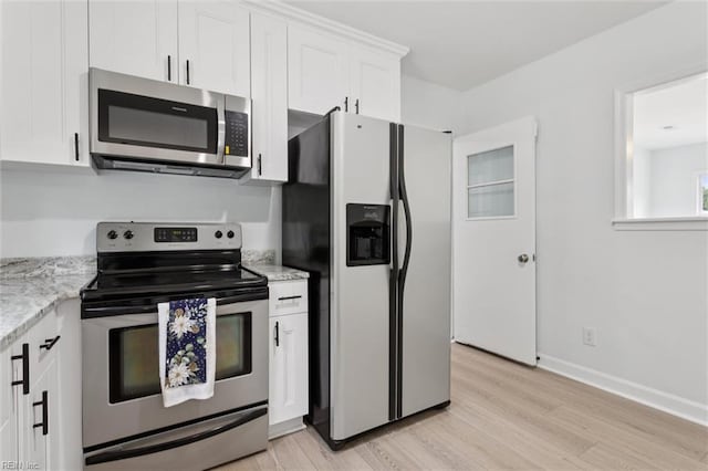 13067 Poor House Rd, Windsor, VA 23487 - kitchen featuring appliances with stainless steel finishes, light wood finished floors, white cabinets, and light stone countertops