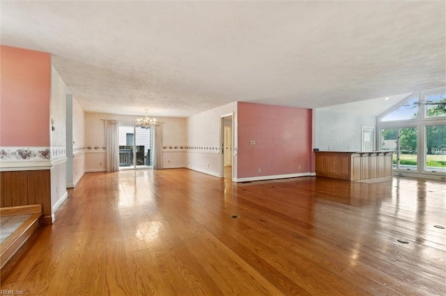133 Randolphs Grn, Williamsburg, VA 23185 - unfurnished living room with a chandelier, healthy amount of natural light, wood finished floors, and a wainscoted wall