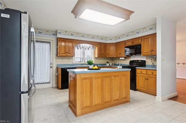 133 Randolphs Grn, Williamsburg, VA 23185 - kitchen featuring black appliances, a center island, light countertops, brown cabinetry, and light floors