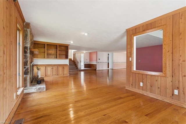 133 Randolphs Grn, Williamsburg, VA 23185 - unfurnished living room featuring light wood-style floors, stairs, wood walls, and a wood stove