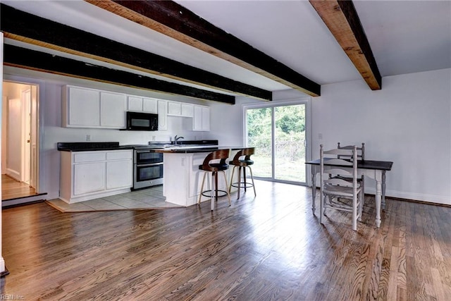 826 Lee St, West Point, VA 23181 - kitchen featuring black microwave, double oven range, light wood finished floors, white cabinetry, and beam ceiling