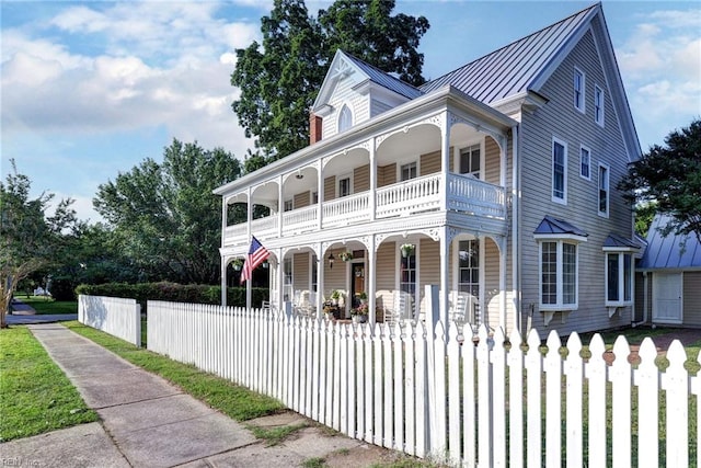 826 Lee St, West Point, VA 23181 - victorian home featuring covered porch, a balcony, a fenced front yard, a standing seam roof, and a metal roof
