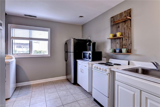 826 Lee St, West Point, VA 23181 - kitchen with stainless steel appliances, washer / dryer, white cabinetry, light countertops, and light tile patterned flooring