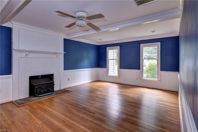 308 Royal Grant Dr, Williamsburg, VA 23185 - unfurnished living room featuring a wainscoted wall, wood finished floors, ceiling fan, crown molding, and a wood stove