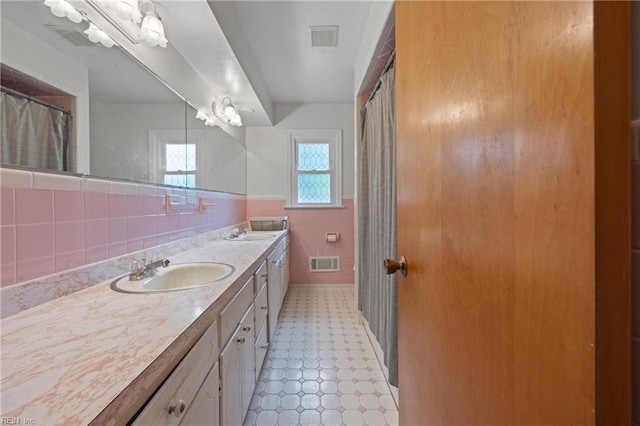 2440 Sir Lance Dr, Chesapeake, VA 23325 - bathroom with tile walls, tile patterned floors, double vanity, and a wainscoted wall