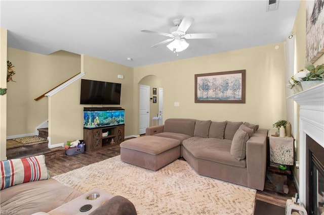 3468 Westham Ln, Toano, VA 23168 - living room with arched walkways, a fireplace, wood finished floors, stairs, and ceiling fan