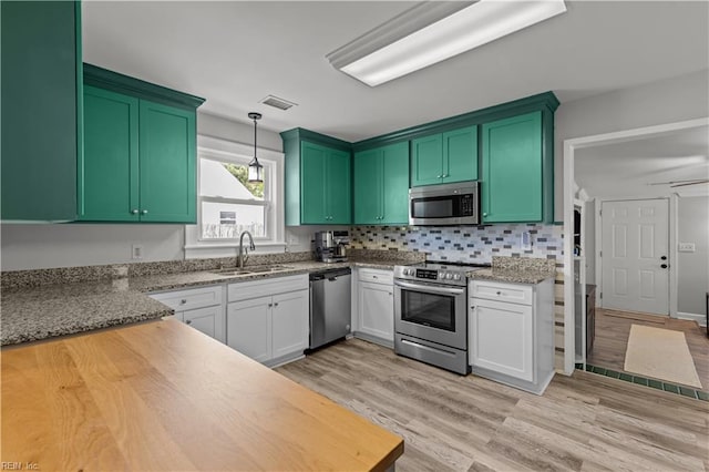 1312 Duncan Ln, Virginia Beach, VA 23455 - kitchen with appliances with stainless steel finishes, light wood-style floors, hanging light fixtures, decorative backsplash, and white cabinetry