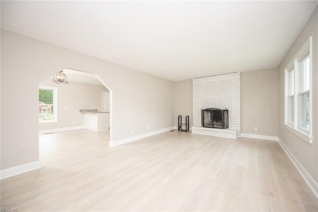 961 Hugo St, Norfolk, VA 23513 - unfurnished living room with light wood-type flooring, a brick fireplace, and arched walkways