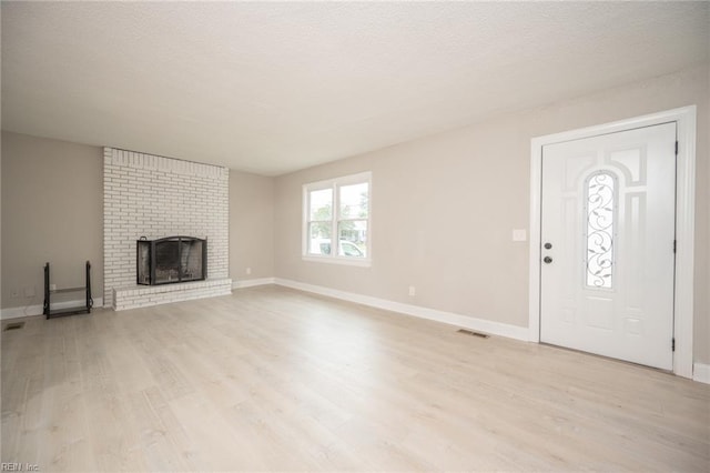 961 Hugo St, Norfolk, VA 23513 - unfurnished living room featuring light wood-style floors, a fireplace, and a textured ceiling