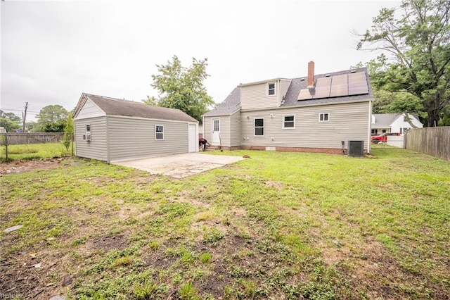 961 Hugo St, Norfolk, VA 23513 - back of property featuring a patio, solar panels, a fenced backyard, an outbuilding, and a chimney
