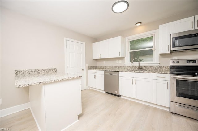 961 Hugo St, Norfolk, VA 23513 - kitchen with appliances with stainless steel finishes, light wood-style flooring, light stone counters, white cabinetry, and a peninsula