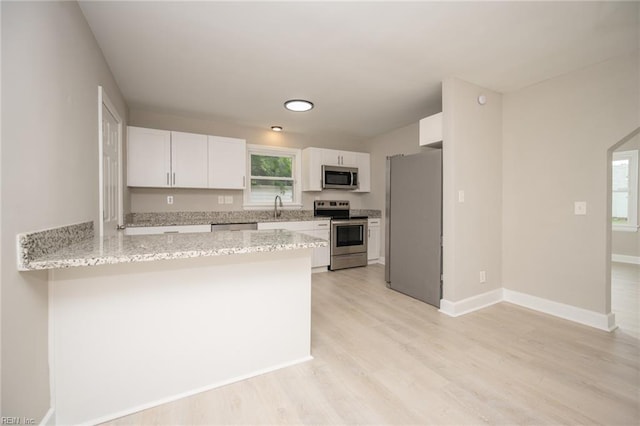 961 Hugo St, Norfolk, VA 23513 - kitchen featuring appliances with stainless steel finishes, a peninsula, white cabinetry, light stone counters, and plenty of natural light