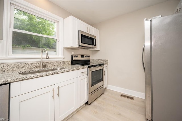 961 Hugo St, Norfolk, VA 23513 - kitchen featuring appliances with stainless steel finishes, light wood-style floors, white cabinets, and light stone counters