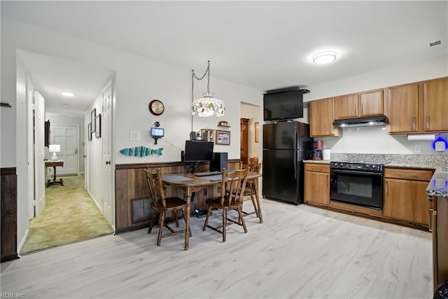 1733 Olde Buckingham Rd, Hampton, VA 23669 - kitchen featuring black appliances, under cabinet range hood, light wood-style floors, wainscoting, and brown cabinetry