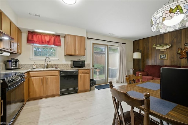1733 Olde Buckingham Rd, Hampton, VA 23669 - kitchen with black appliances, light wood-style floors, wooden walls, light stone counters, and open floor plan