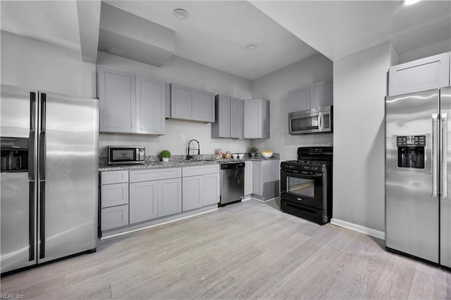 1047 26th St, Newport News, VA 23607 - kitchen with stainless steel appliances, light wood-style floors, gray cabinetry, and light stone counters