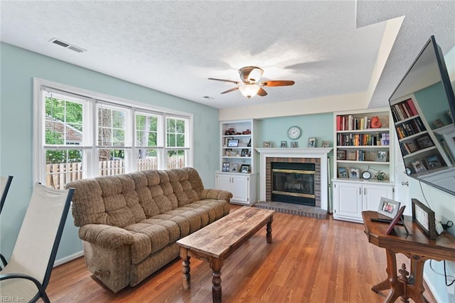 301 Ashland Ct, Newport News, VA 23606 - living room with a ceiling fan, a textured ceiling, wood finished floors, a brick fireplace, and built in shelves