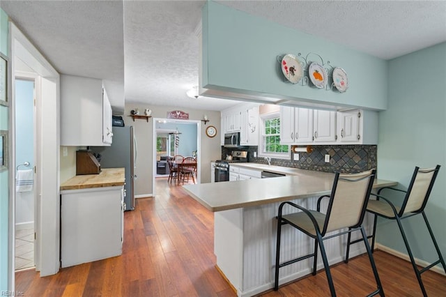 301 Ashland Ct, Newport News, VA 23606 - kitchen with appliances with stainless steel finishes, a textured ceiling, a peninsula, decorative backsplash, and white cabinetry