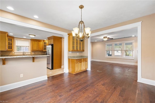 1718 Fontainebleau Cres, Norfolk, VA 23509 - kitchen featuring brown cabinets, freestanding refrigerator, a breakfast bar, a chandelier, and healthy amount of natural light