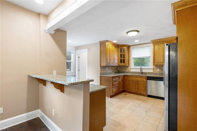 1718 Fontainebleau Cres, Norfolk, VA 23509 - kitchen with stainless steel appliances, a peninsula, brown cabinets, a breakfast bar area, and light stone countertops