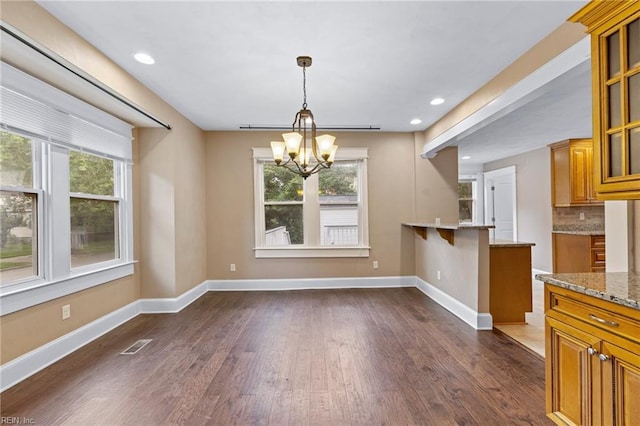 1718 Fontainebleau Cres, Norfolk, VA 23509 - kitchen with brown cabinetry, a chandelier, dark wood finished floors, light stone counters, and glass insert cabinets