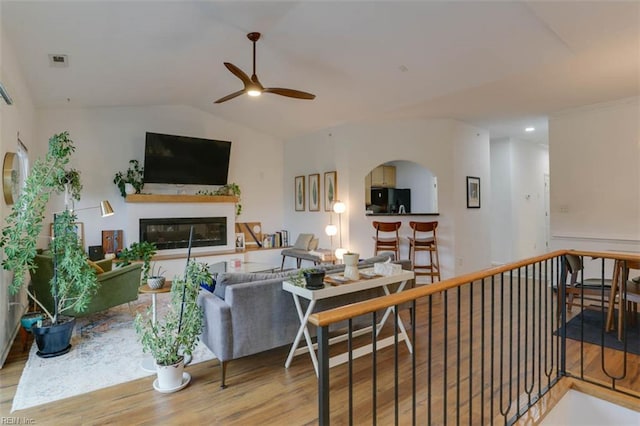 1004 Rustads Cir, Williamsburg, VA 23188 - living room featuring ceiling fan, wood finished floors, a glass covered fireplace, lofted ceiling, and arched walkways