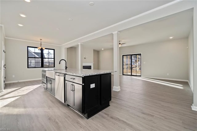 2245 Captiva Ln, Chesapeake, VA 23321 - kitchen featuring stainless steel dishwasher, light wood-style flooring, an island with sink, a fireplace, and dark cabinetry