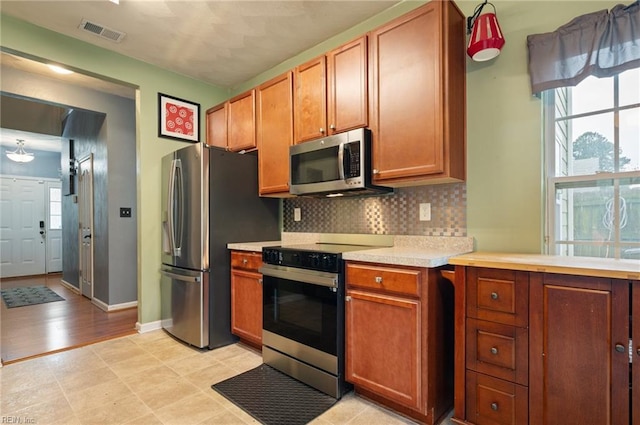 2559 Golden Maple Dr, Suffolk, VA 23434 - kitchen featuring appliances with stainless steel finishes, light countertops, backsplash, and brown cabinets
