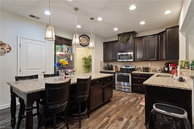 180 Avon Rd, Hampton, VA 23666 - kitchen with appliances with stainless steel finishes, a kitchen island, dark wood-type flooring, dark brown cabinetry, and light stone counters
