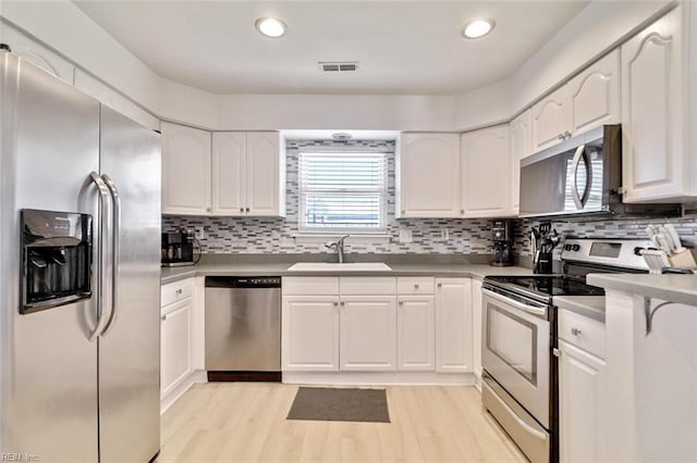 1256 Etworth Ln, Virginia Beach, VA 23464 - kitchen with appliances with stainless steel finishes, white cabinets, light wood-type flooring, decorative backsplash, and recessed lighting
