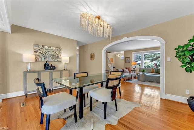 241 Sir Oliver Rd, Norfolk, VA 23505 - dining space with arched walkways, a chandelier, light wood finished floors, and decorative columns