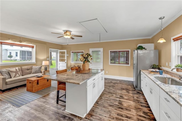 241 Sir Oliver Rd, Norfolk, VA 23505 - kitchen with healthy amount of natural light, crown molding, freestanding refrigerator, white cabinets, and a breakfast bar area