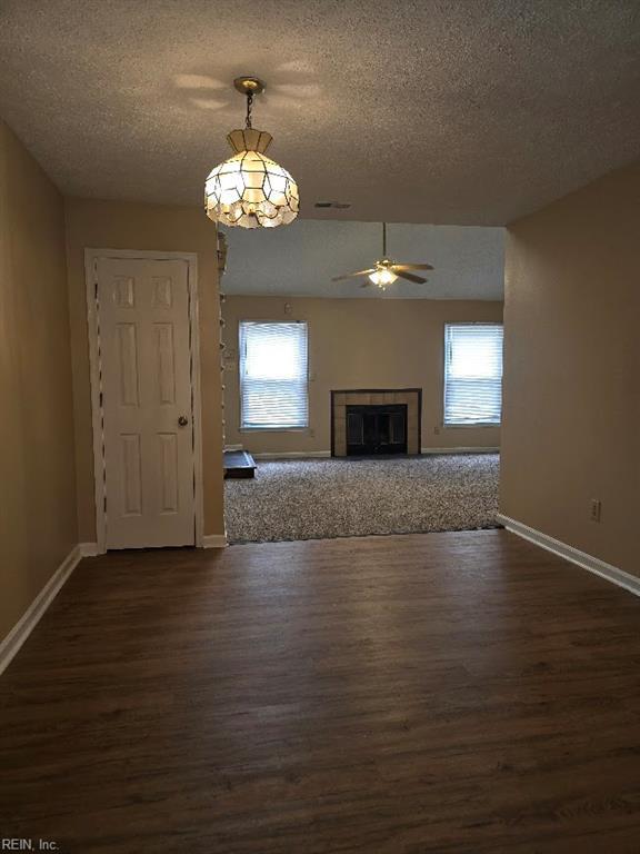 238 Susan Constant Dr, Newport News, VA 23608 - unfurnished living room with dark wood-style flooring, a textured ceiling, a ceiling fan, and a tile fireplace