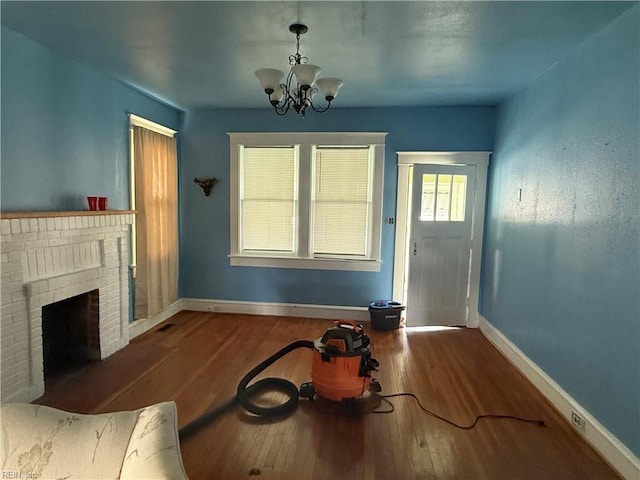 261 N First St, Hampton, VA 23664 - unfurnished living room with hardwood / wood-style flooring, a chandelier, and a brick fireplace