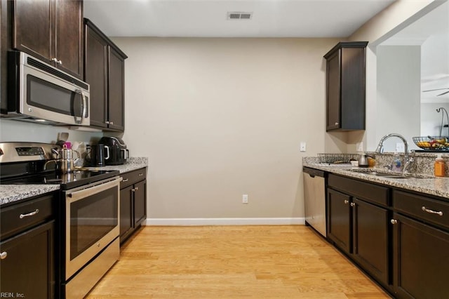 705 Braemar Crk, Williamsburg, VA 23188 - kitchen featuring appliances with stainless steel finishes, light wood-style floors, dark brown cabinets, and light stone countertops