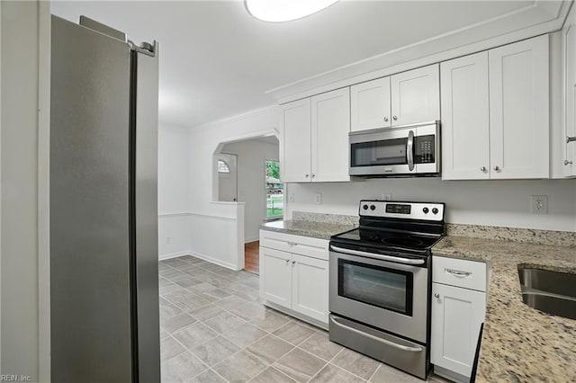 1207 Hazel Ave, Chesapeake, VA 23325 - kitchen featuring appliances with stainless steel finishes, white cabinets, arched walkways, crown molding, and light stone counters