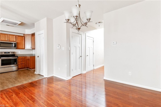 222 Craftsman Cir, Suffolk, VA 23434 - kitchen featuring stainless steel appliances, brown cabinetry, wood finished floors, a chandelier, and hanging light fixtures