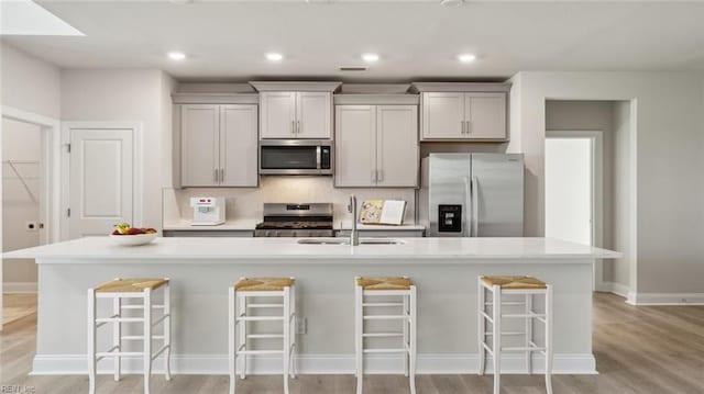 2017 Munro Ln, Chesapeake, VA 23322 - kitchen featuring appliances with stainless steel finishes, light wood-type flooring, a kitchen breakfast bar, gray cabinetry, and light countertops