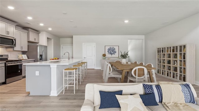 2017 Munro Ln, Chesapeake, VA 23322 - kitchen with stainless steel appliances, gray cabinets, light wood-style flooring, a center island with sink, and recessed lighting