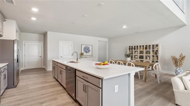 2017 Munro Ln, Chesapeake, VA 23322 - kitchen with appliances with stainless steel finishes, a center island with sink, light countertops, gray cabinets, and light wood-style flooring